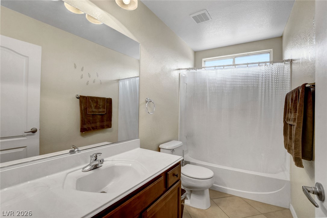 Bathroom with dark wood vanity, large mirror, and tub-shower beneath a window.