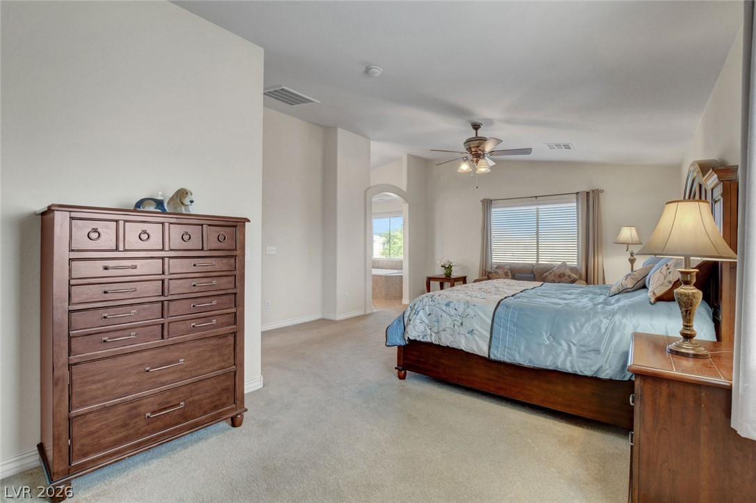 Furnished bedroom with pale blue bedding, dark wood furniture, and an arched doorway.