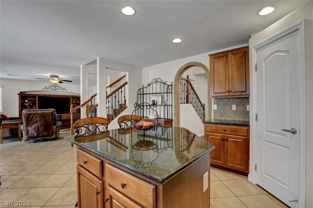 Kitchen with a granite-topped island, warm wood cabinets, and wrought-iron details.