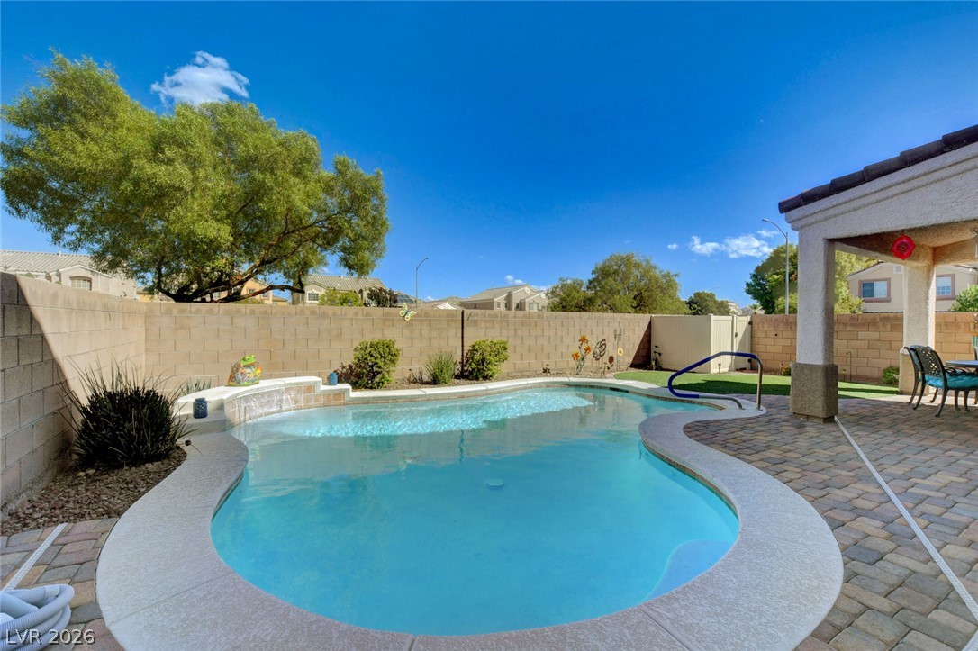 Backyard pool with curved coping, paver deck, and covered patio.