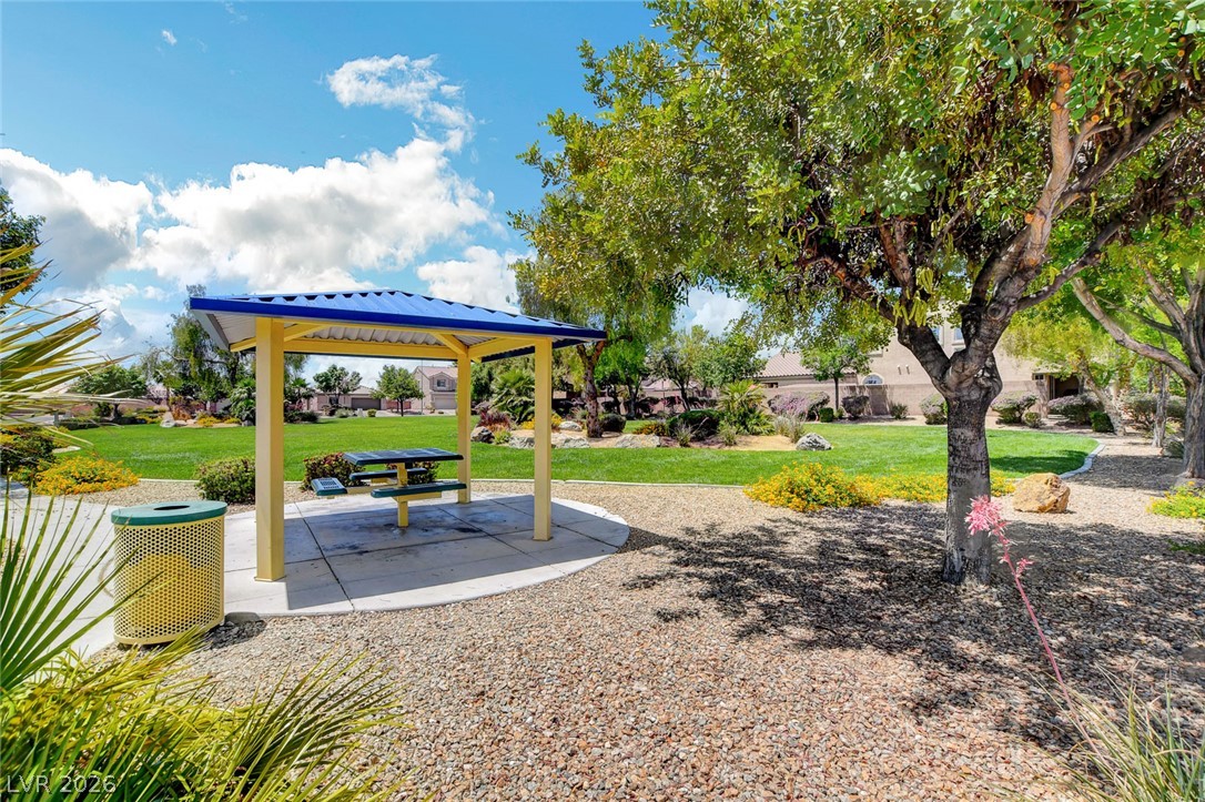 Neighborhood park pavilion with a picnic table, mature trees, and a broad green lawn.