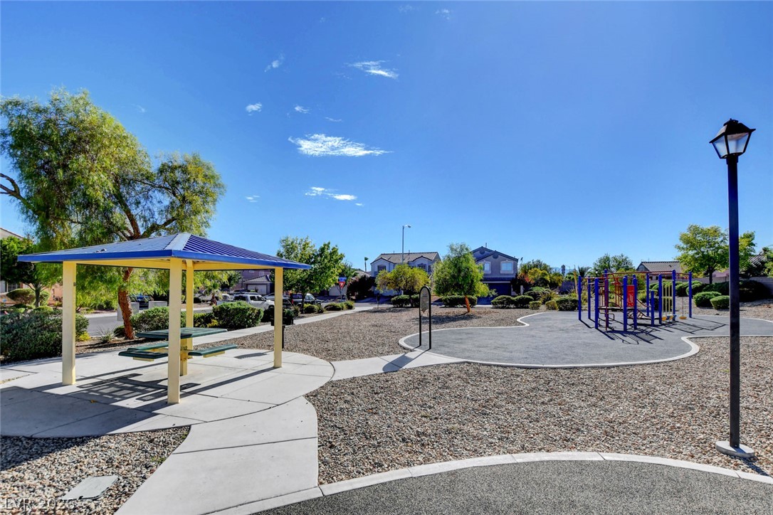Neighborhood park with a colorful playground, picnic shelter, and curving paved paths.