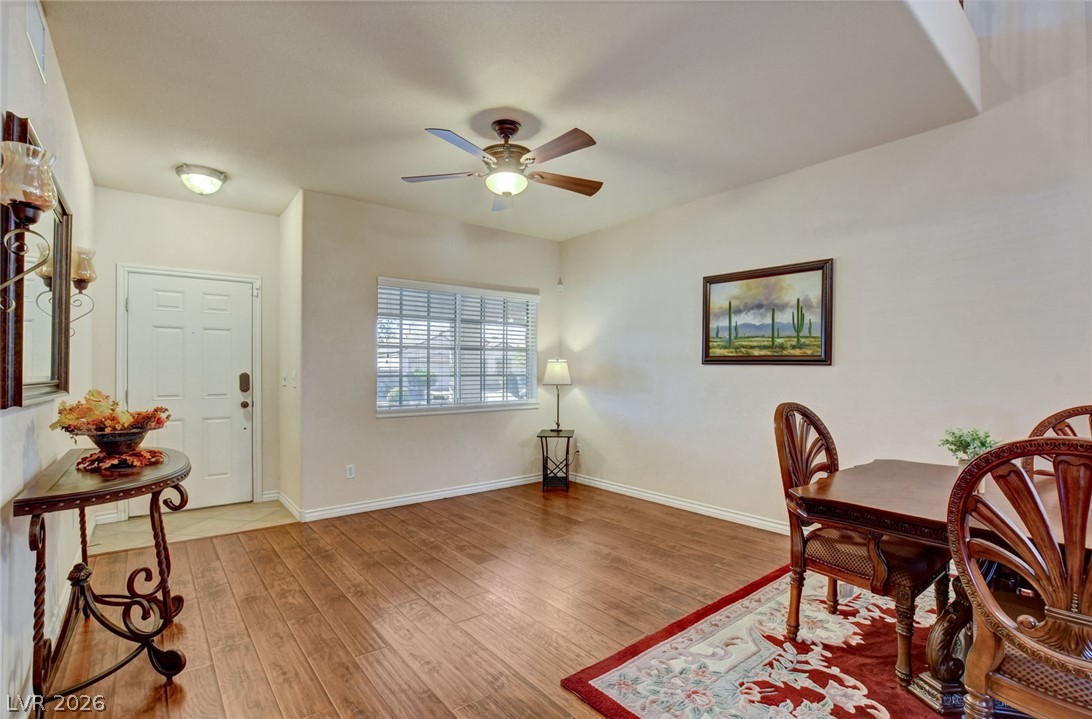 Dining room with a wood table and carved chairs, ceiling fan, and entry door.