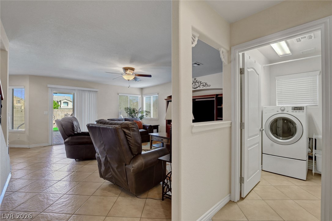Living room with leather recliners and tiled floors beside a laundry room with a front-loading washer.