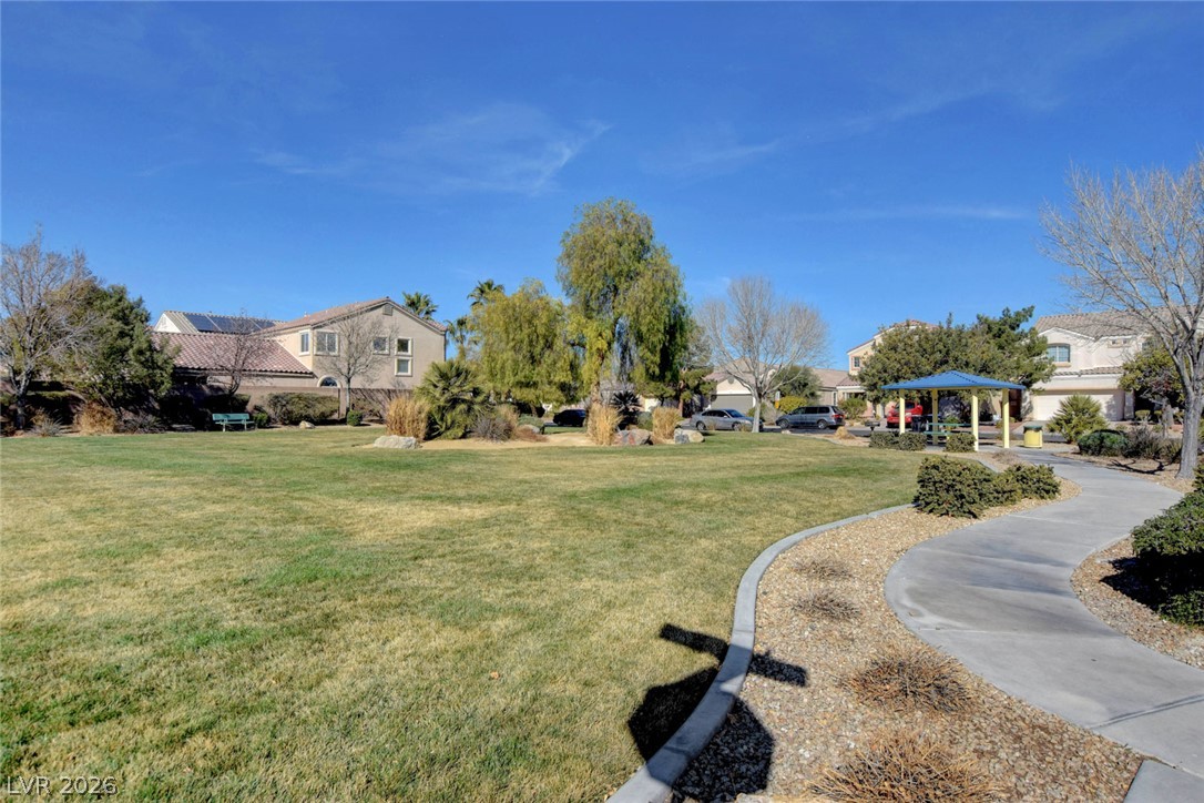 Community green space with a curving walkway, mature trees, and a blue-roofed gazebo.