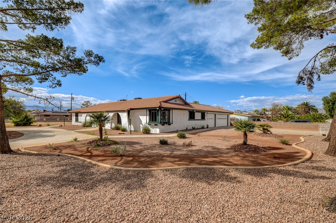 Single-story stucco home with a reddish tile roof, attached garage, and desert gravel landscaping.