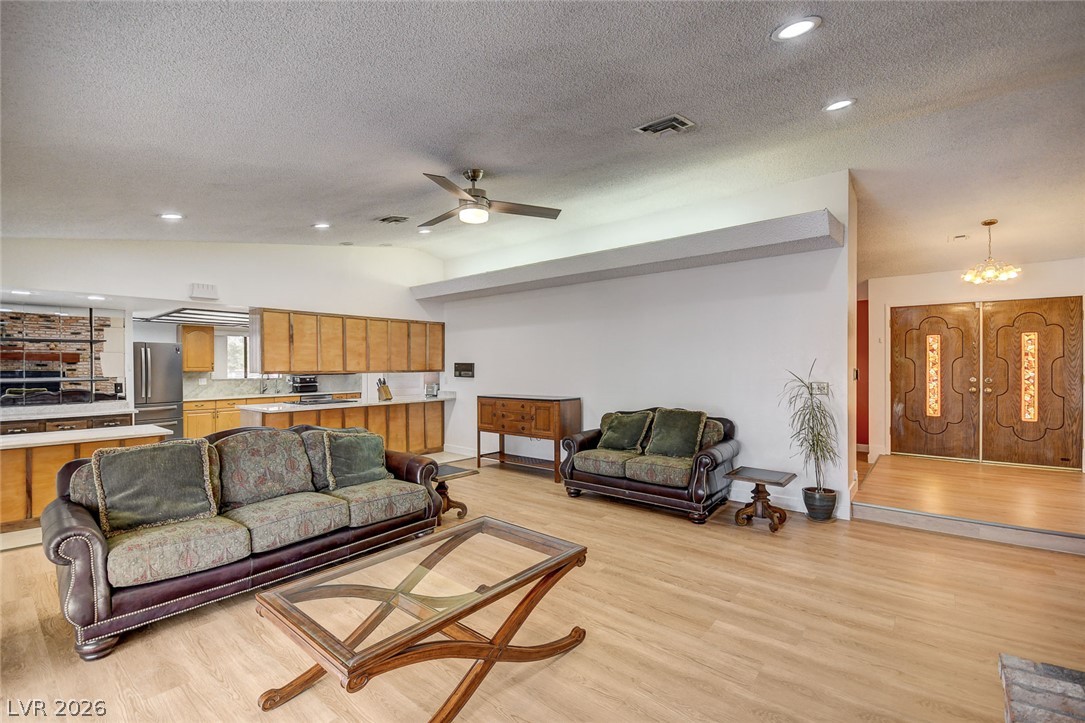 Open-plan living room with two leather sofas, wood cabinetry, and ornate double entry doors.