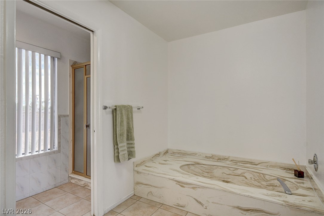 Bathroom with a large marbled built-in tub beside a glass-enclosed shower.