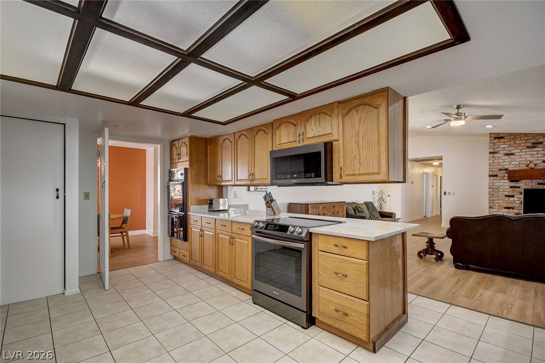 Kitchen with wood cabinets, a white island, stainless appliances, and a dark-beamed ceiling.