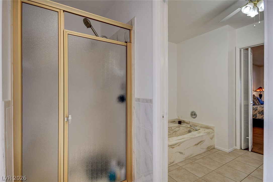 Bathroom with a frosted-glass shower and a jetted tub with a marble-look surround.