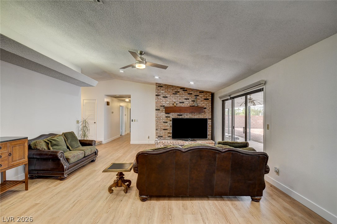 Living room with a brick fireplace, leather sofas, and sliding glass doors to a covered patio.