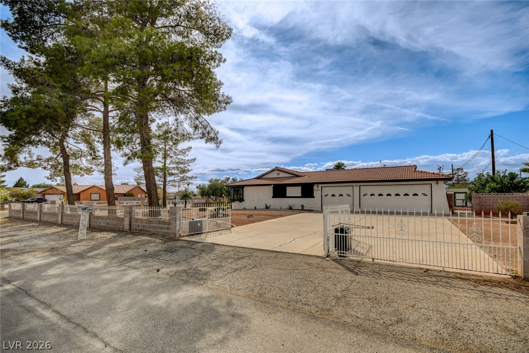 Single-story home with a gated driveway, two-car garage, and tall pine trees.