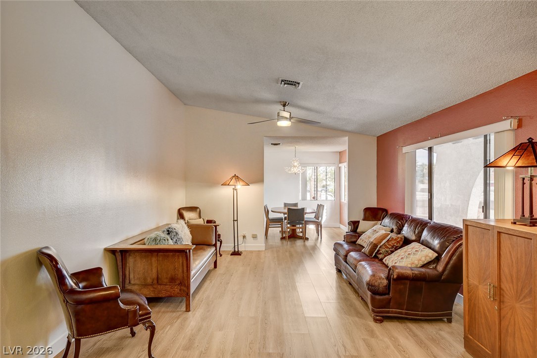 Living room with brown leather seating, a red accent wall, and an adjoining dining area.