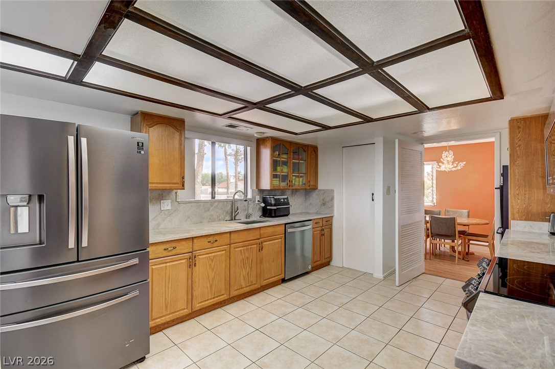 Kitchen with honey-colored cabinets, stainless steel appliances, and a dark wood-beamed ceiling.