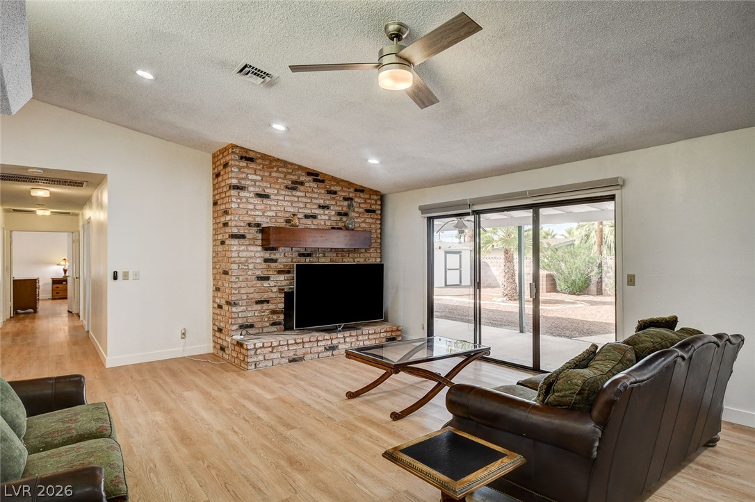 Living room with a brick fireplace, leather sofas, and sliding glass doors to the yard.