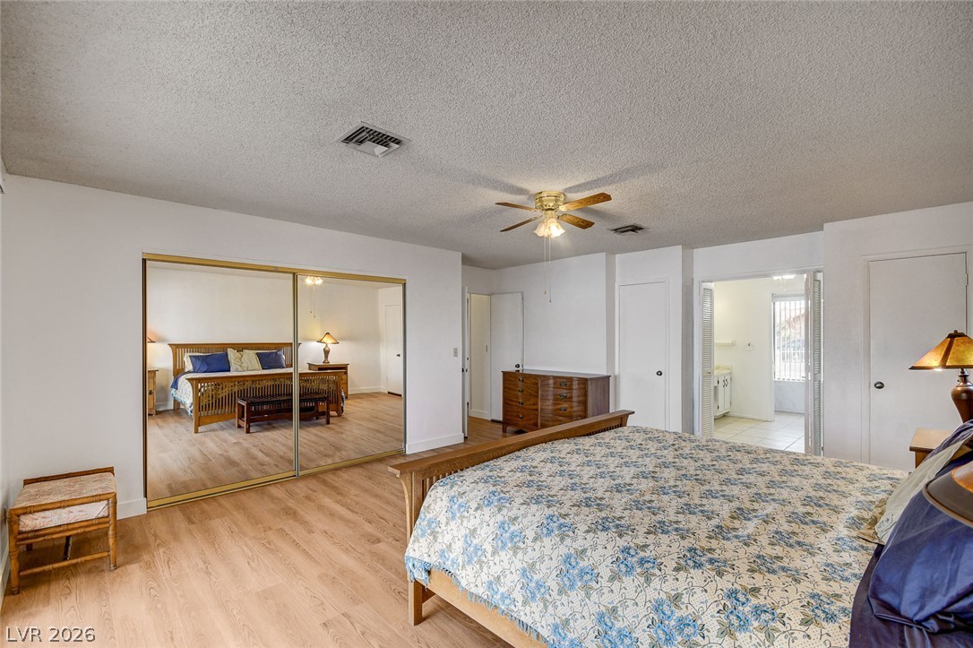 Bedroom with a floral bedspread, ceiling fan, and mirrored sliding closet doors.