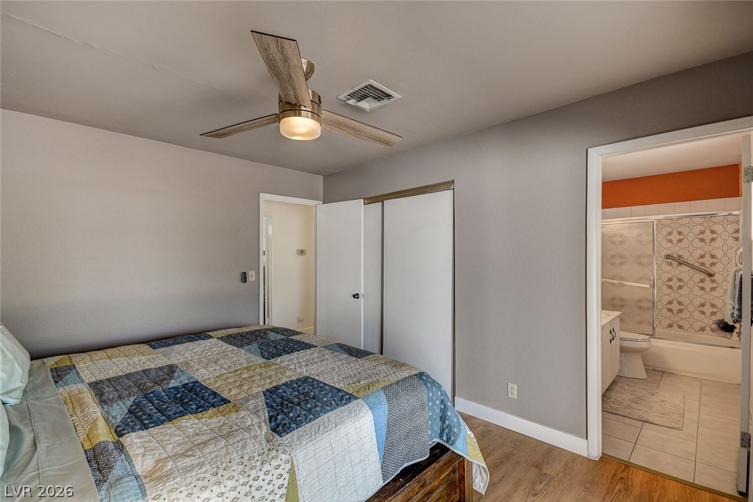 Furnished bedroom with a patchwork quilt, ceiling fan, and adjoining bathroom.