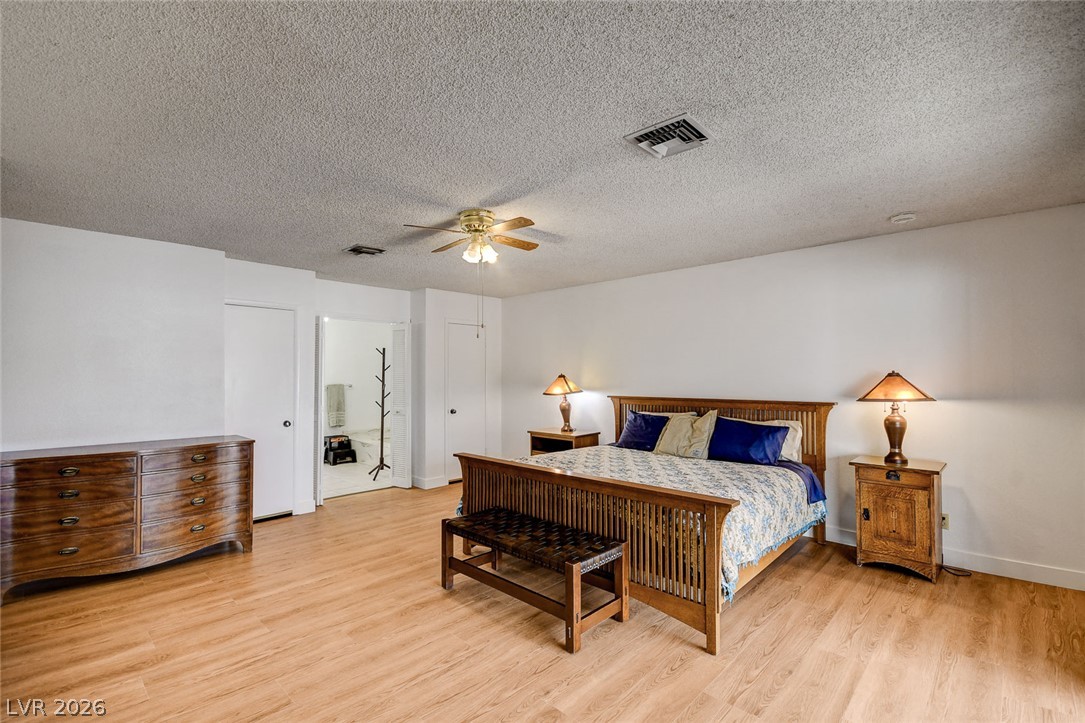 Bedroom with a wooden bed, blue pillows, matching nightstands, and light wood flooring.