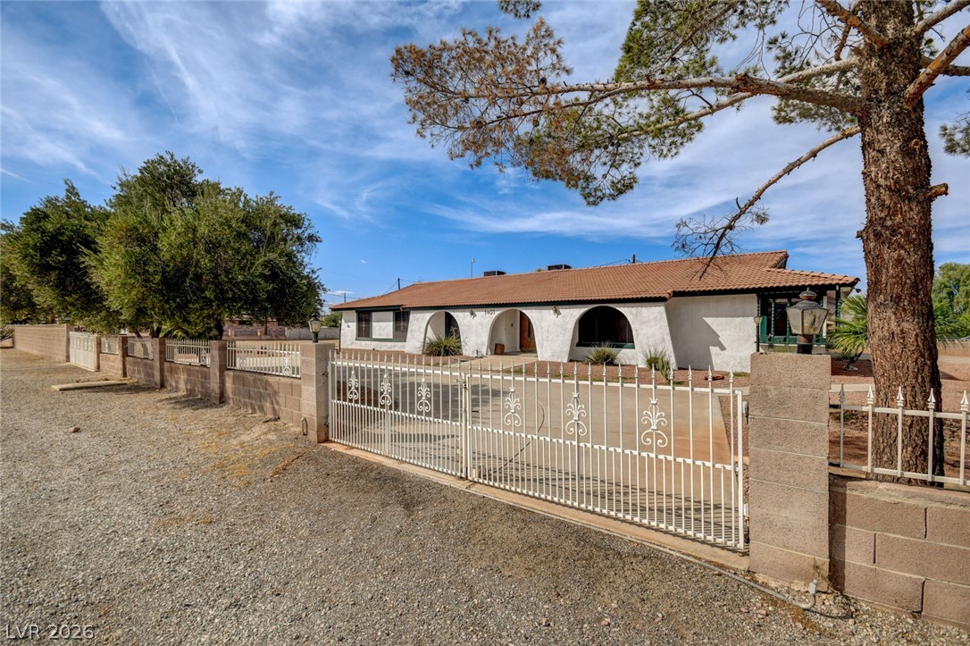 Single-story stucco home with arched porch, terracotta roof, and decorative metal gate.