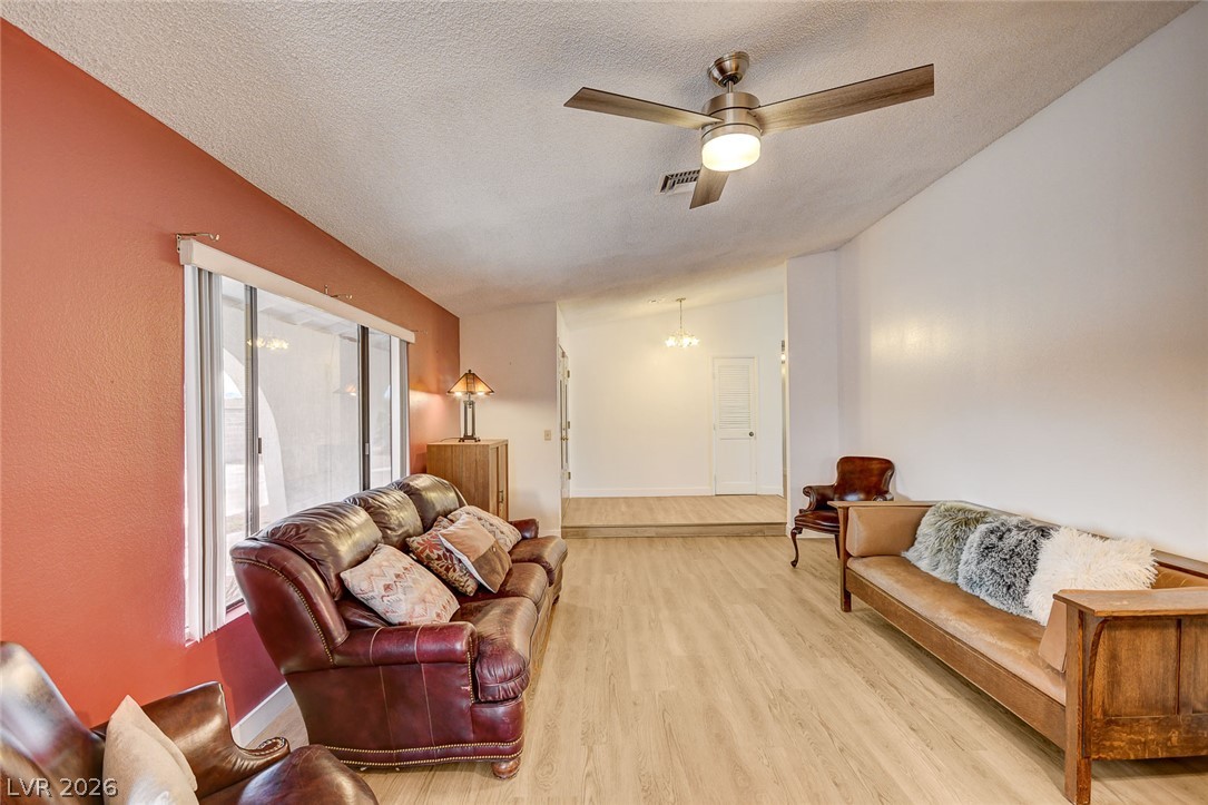Living room with a red accent wall, sliding doors, leather seating, and a ceiling fan.