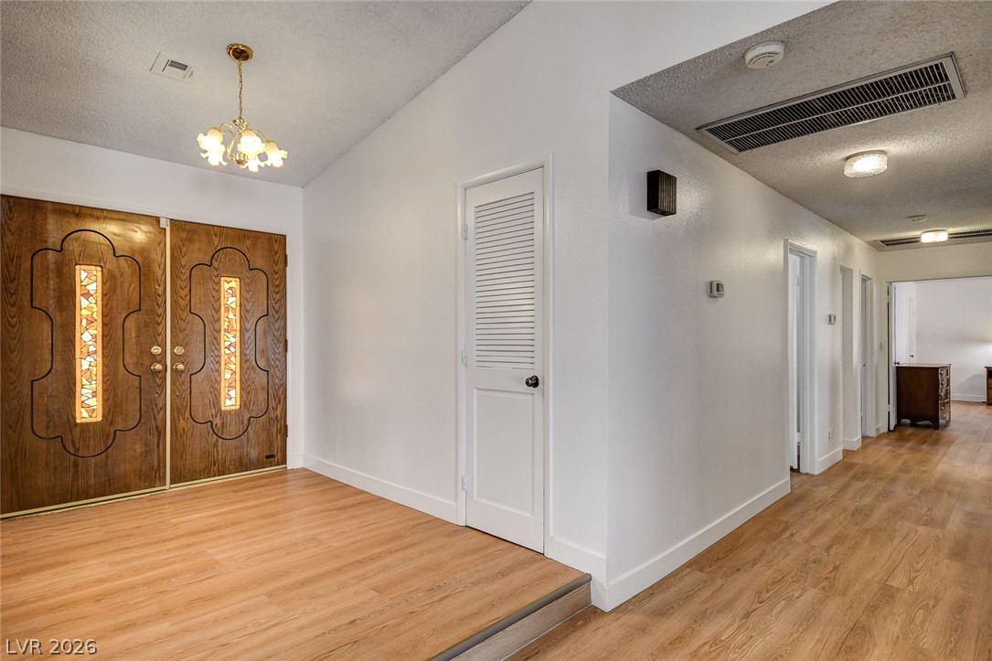 Entryway with ornate wooden double doors, stained-glass panels, and a wood-floored hallway.