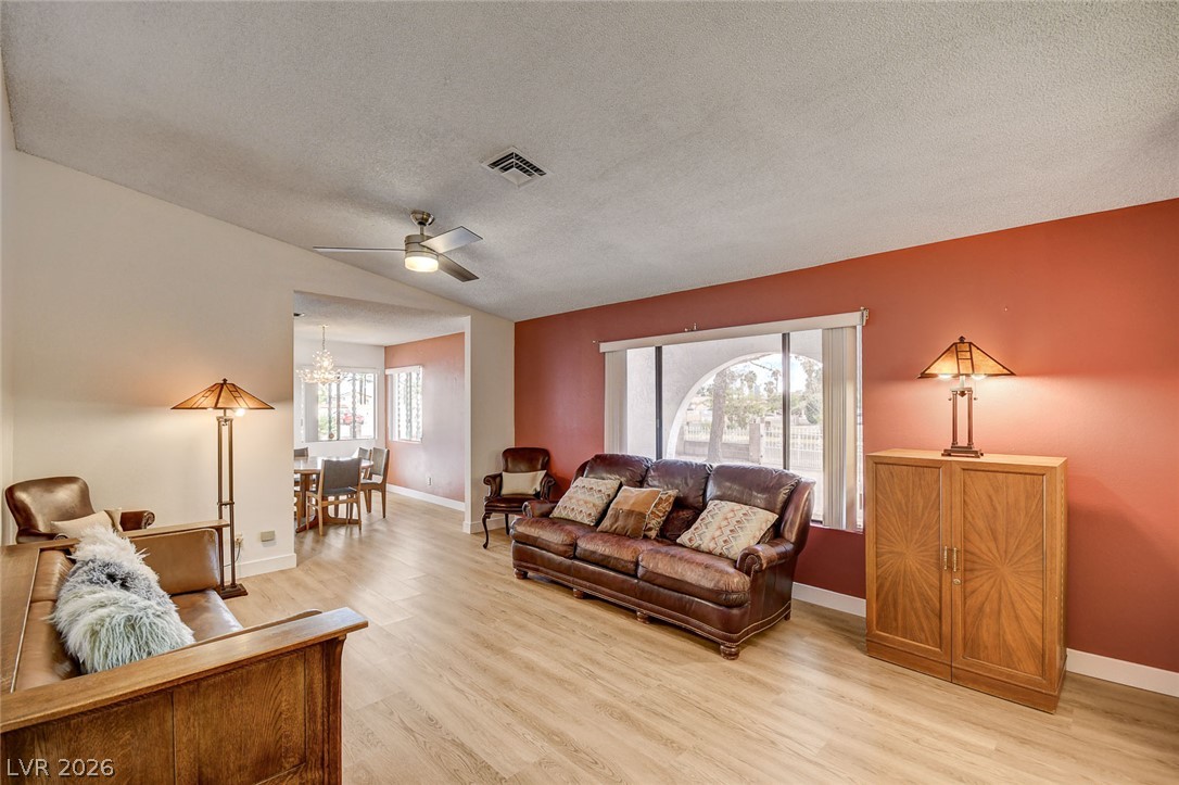 Living room with leather sofas, a red accent wall, and a dining area beyond.