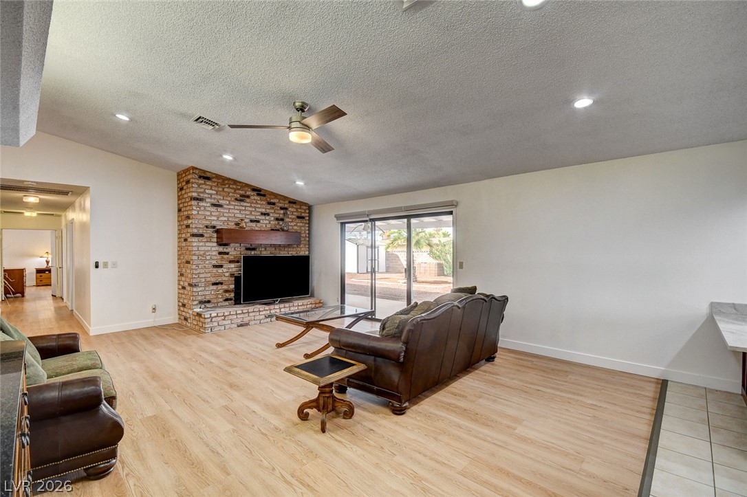 Living room with leather sofas, a brick fireplace, and sliding glass doors to the backyard.