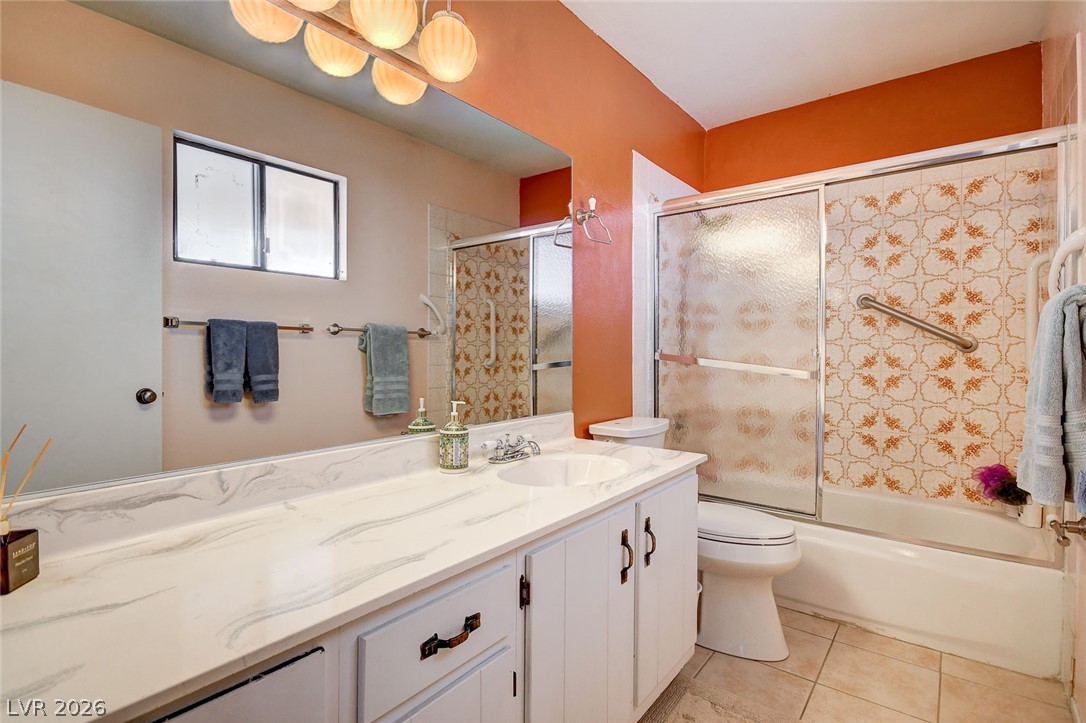 Bathroom with a long marble-pattern vanity and bathtub with patterned tile and frosted sliding doors.