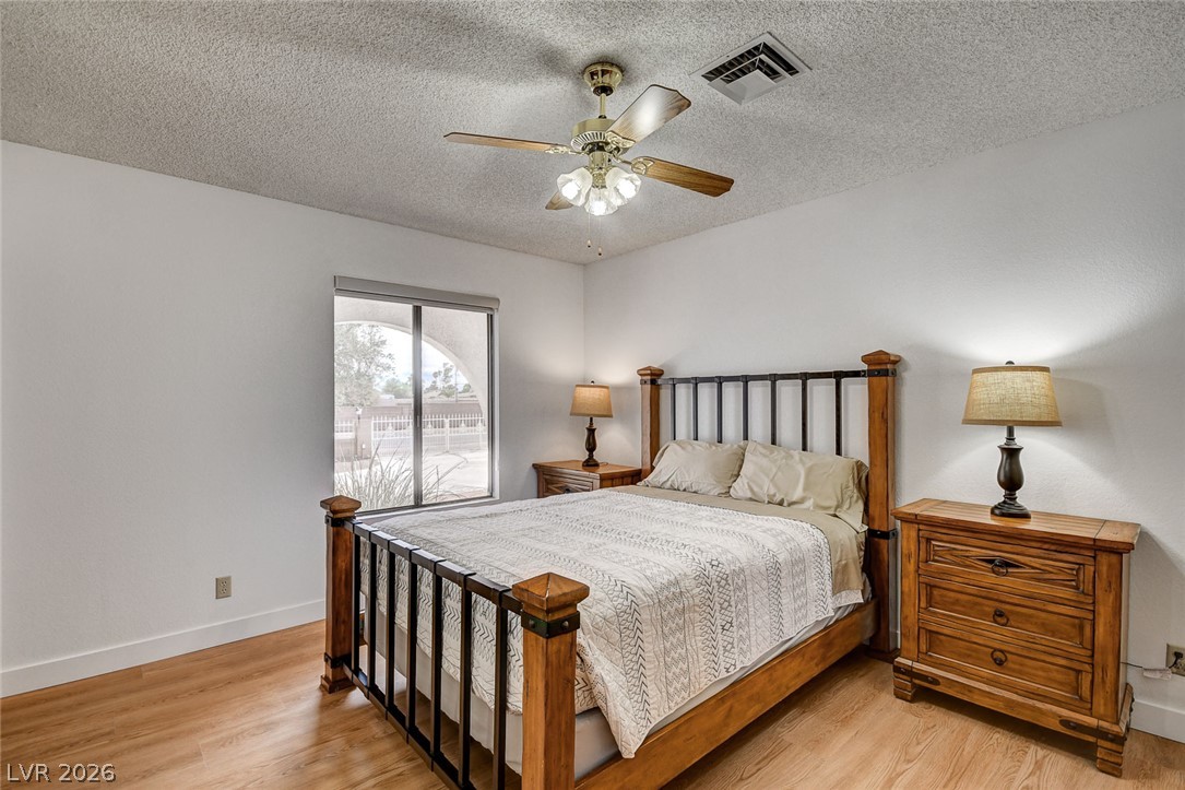 Furnished bedroom with a wooden bed, matching nightstands, and sliding glass door to a patio.
