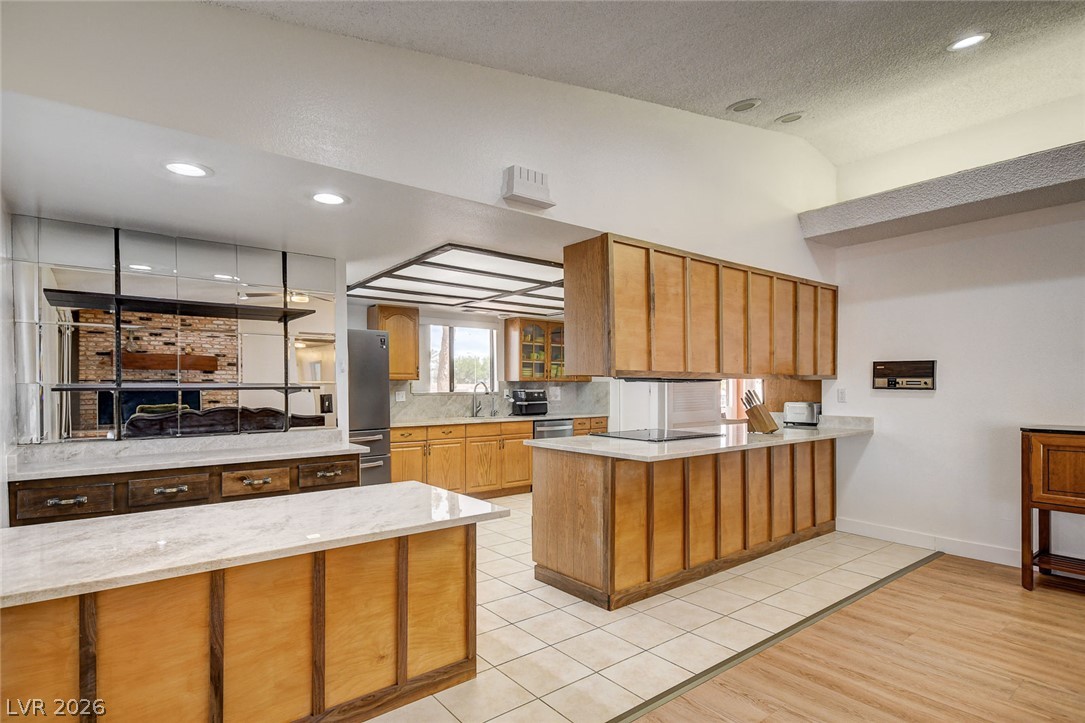 Kitchen with warm wood cabinetry, white counters, and a large central island.