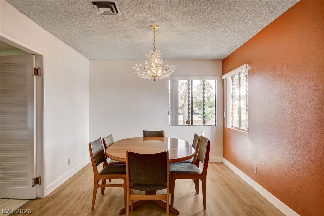Dining room with a round table, crystal chandelier, and orange accent wall.