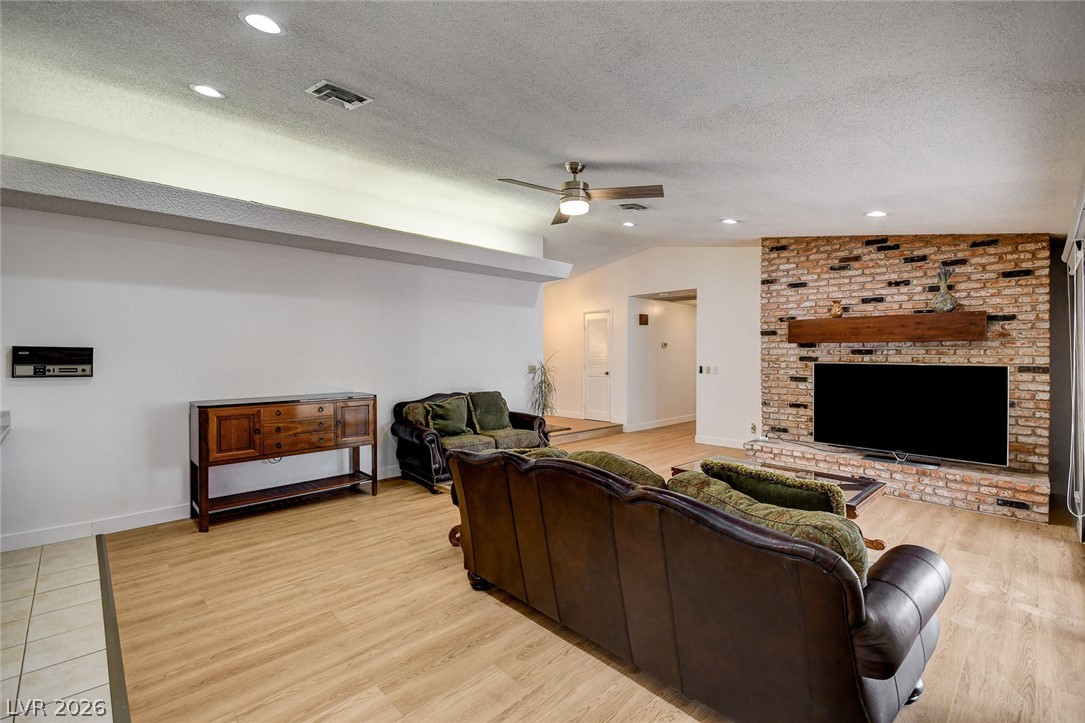 Living room with leather seating, light wood floors, and a brick fireplace wall.