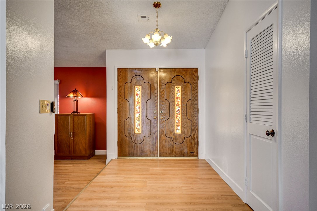 Entry foyer with carved wooden double doors, stained-glass panels, and a red accent wall.