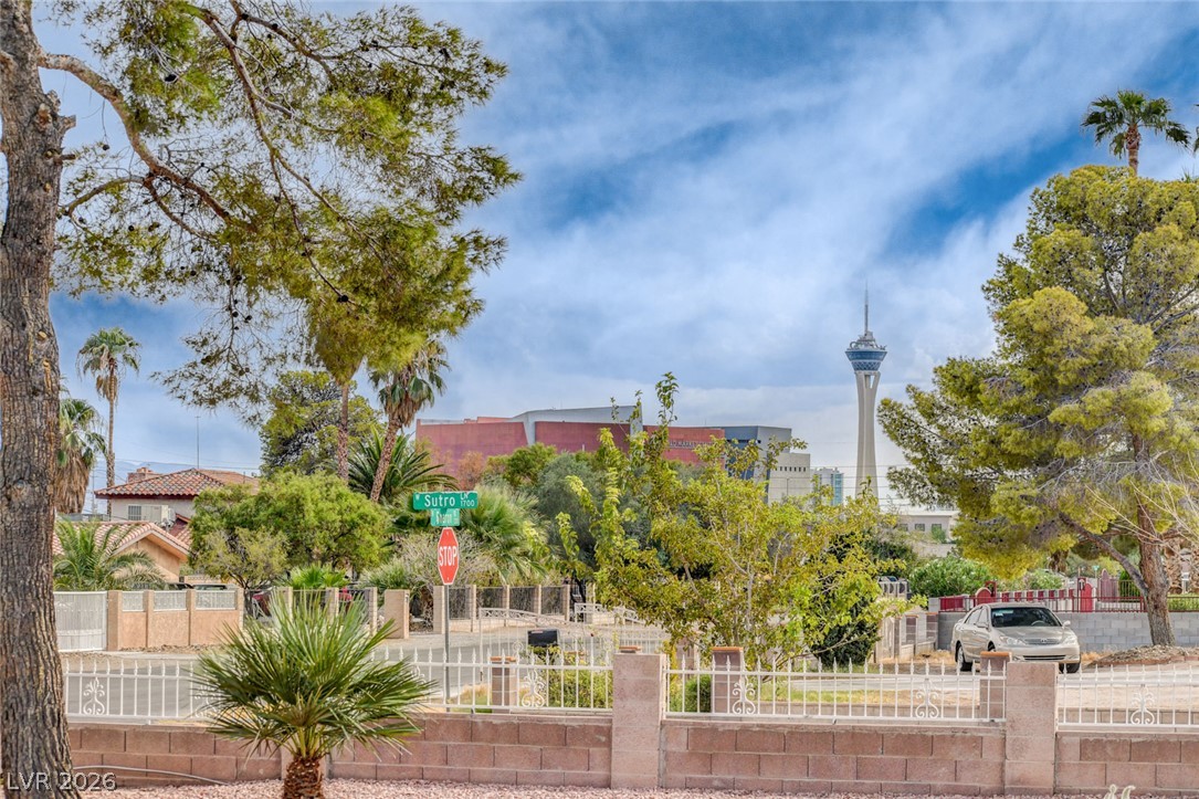 Las Vegas homes behind a low wall and fence, with mature trees and the Stratosphere Tower in the distance.