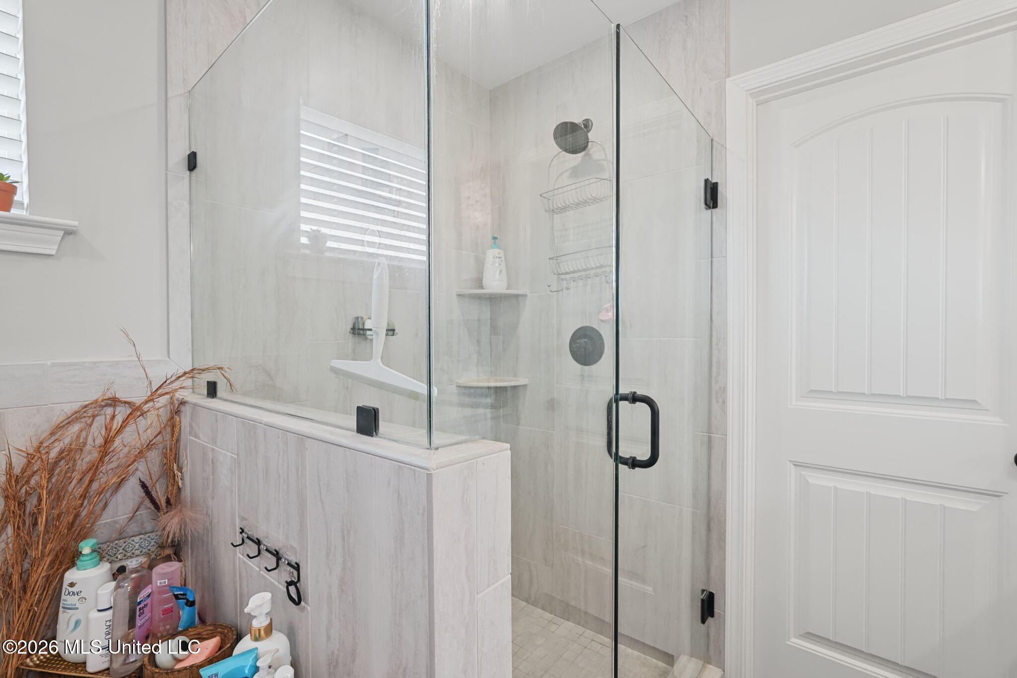 Bathroom with a glass-enclosed tiled walk-in shower and black fixtures.