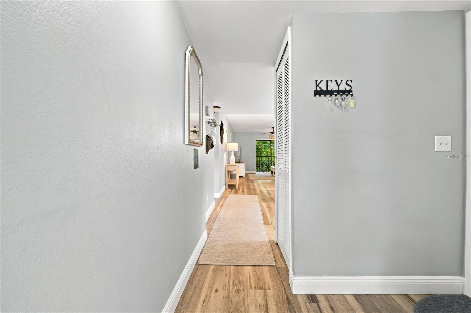 Condo entry hallway with wood-look floors, a runner rug, and a key rack labeled “KEYS.”