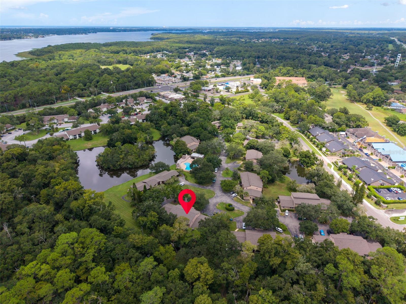 Aerial view of wooded condominiums beside waterways, with one unit marked in red.