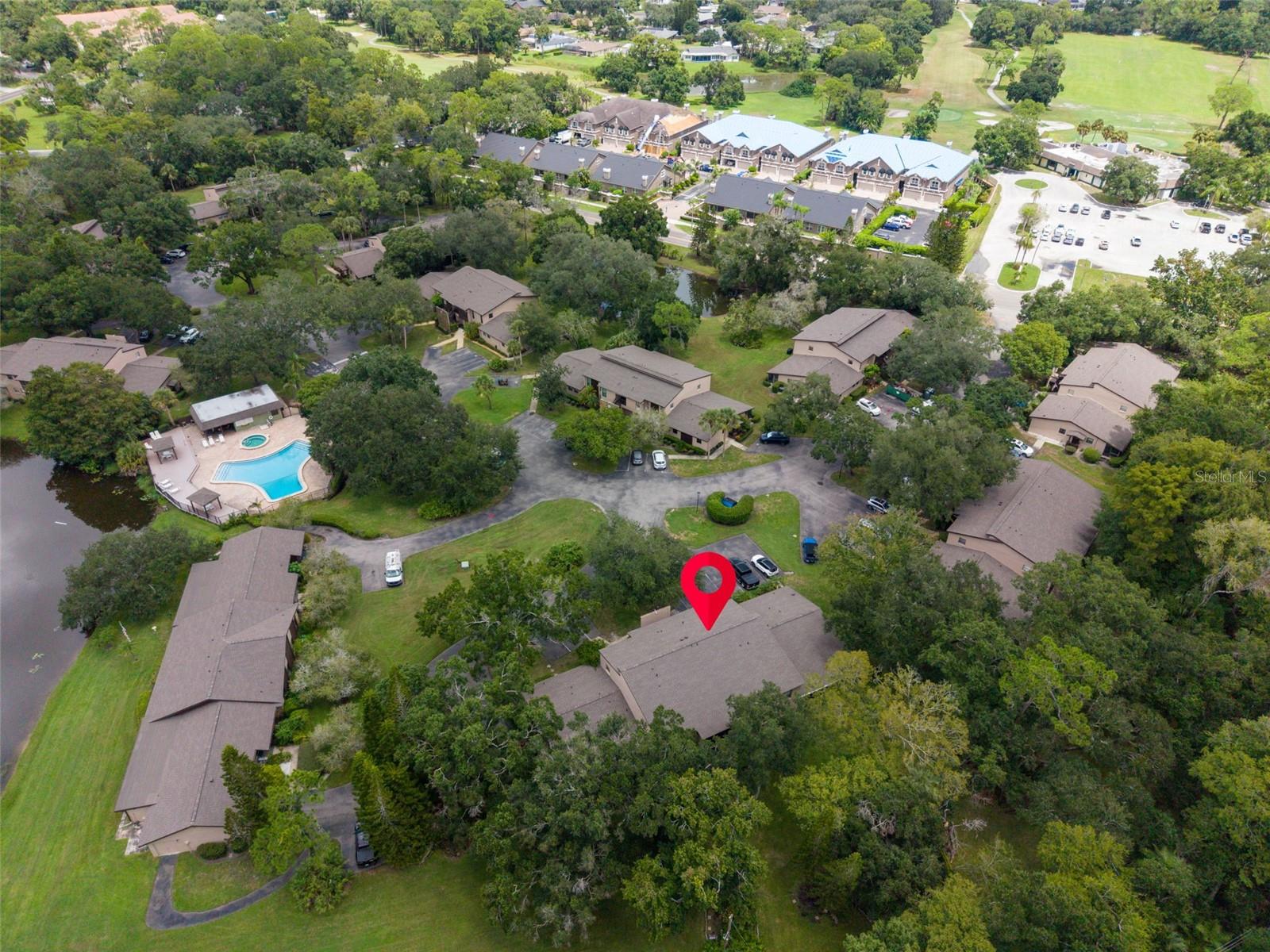Aerial view of the condominium community, with the marked unit near a pool and landscaped grounds.
