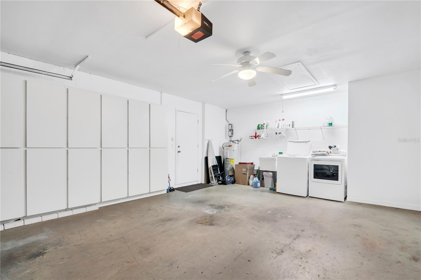 Garage with extensive wall cabinets, washer and dryer, and a bare concrete floor.