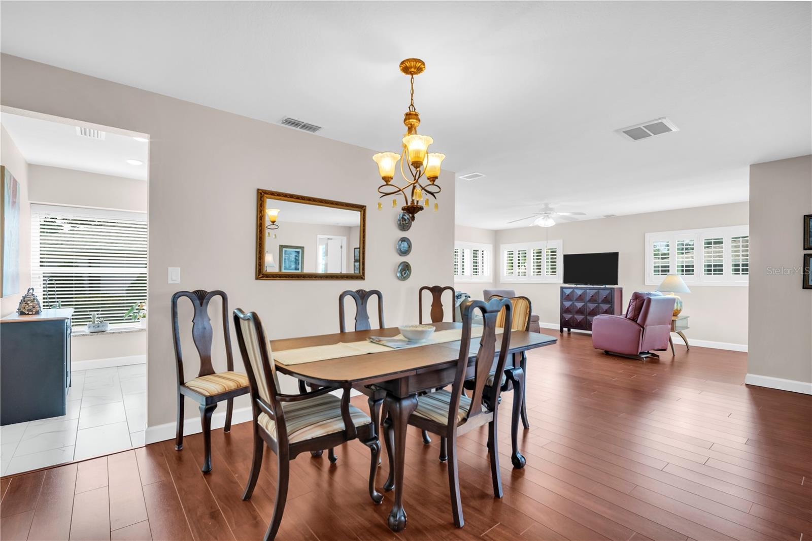 Dining and living area with a dark wood table, chandelier, and purple armchairs.