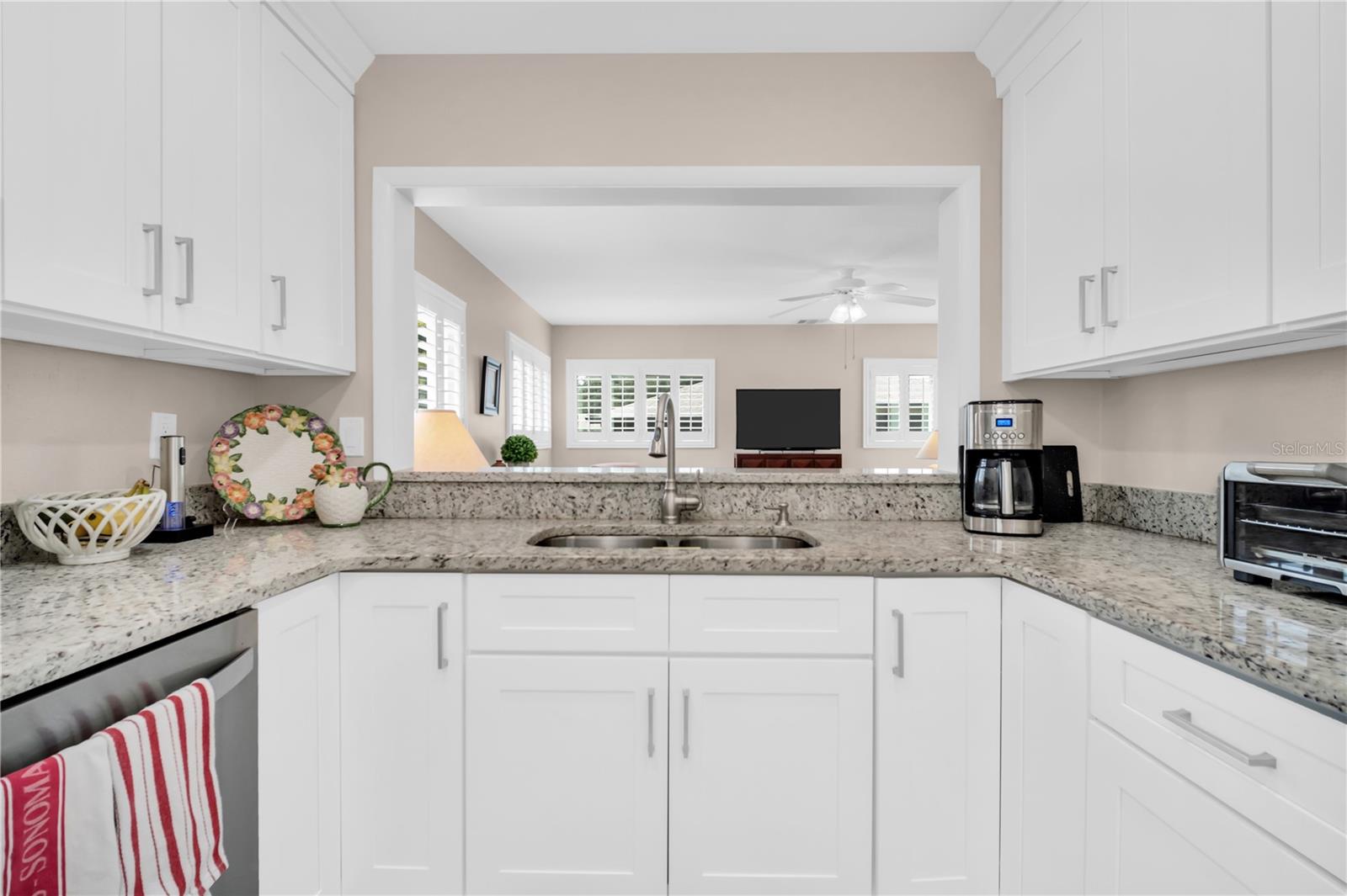 Bright white kitchen with granite counters and a wide opening to the living room.