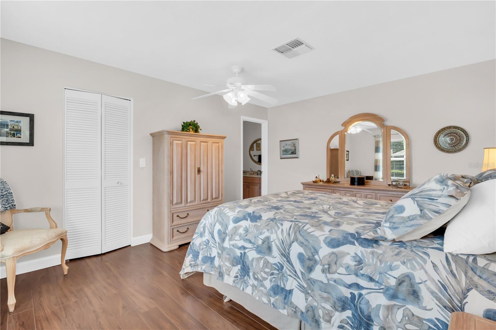 Furnished bedroom with blue-and-white floral bedding and a light wood vanity with an arched mirror.