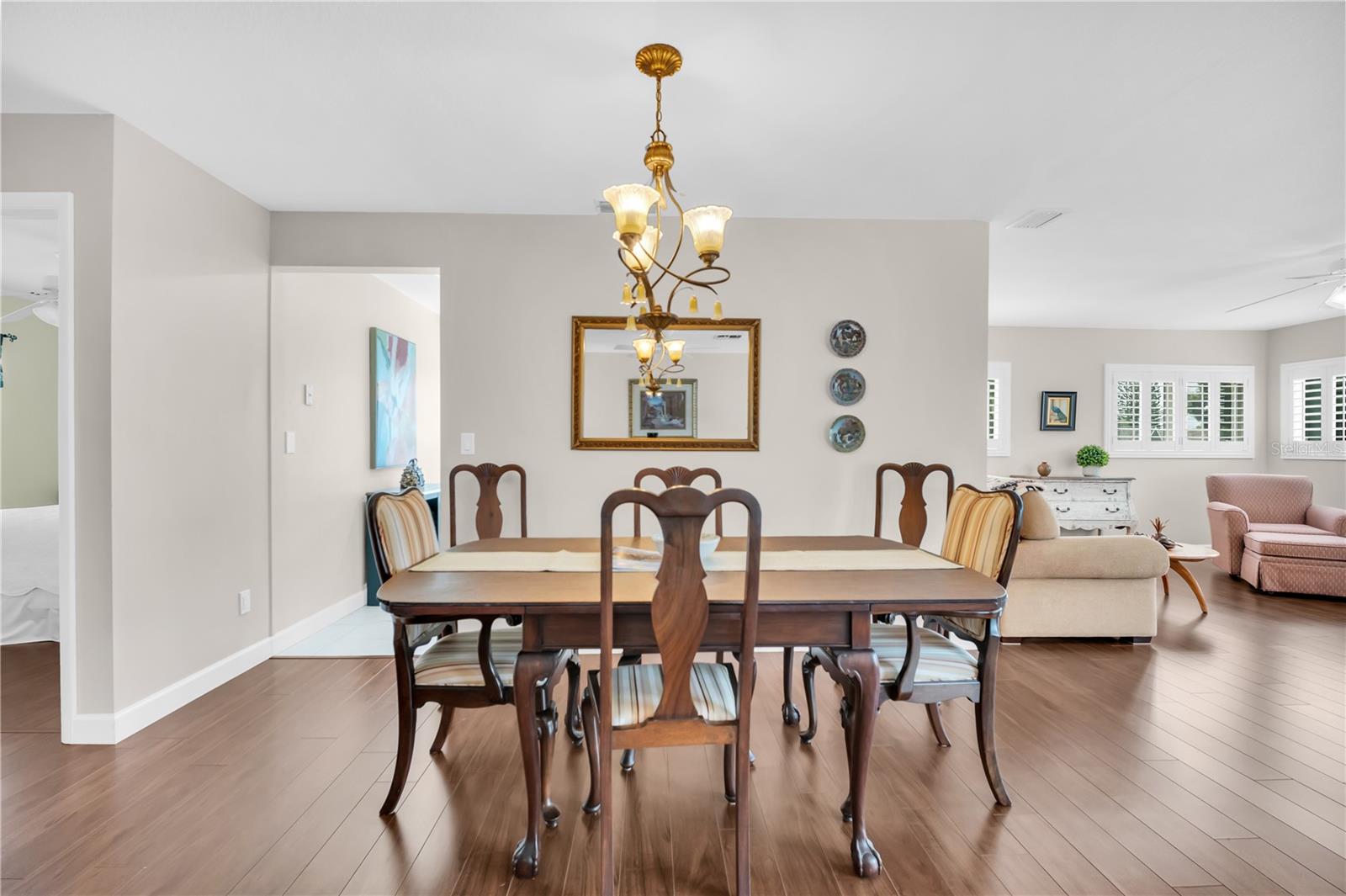 Dining room with a dark wood table, brass chandelier, and open view into the living area.