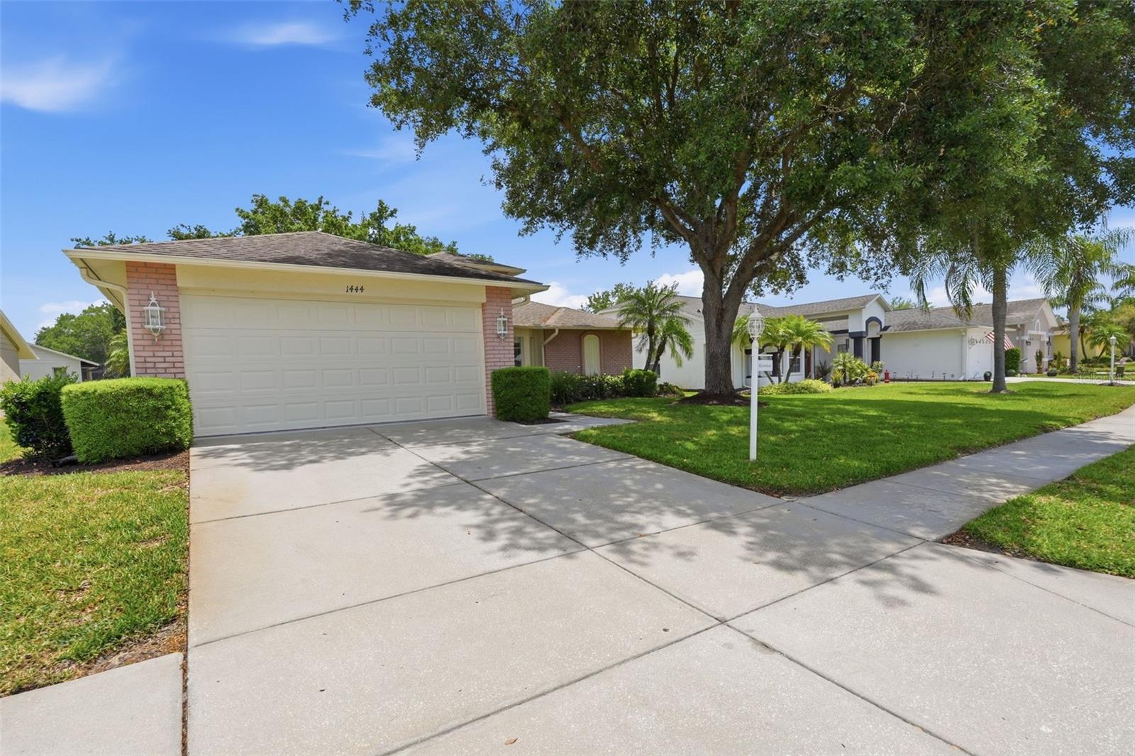 Single-story home with a wide garage and driveway beneath a large shade tree.