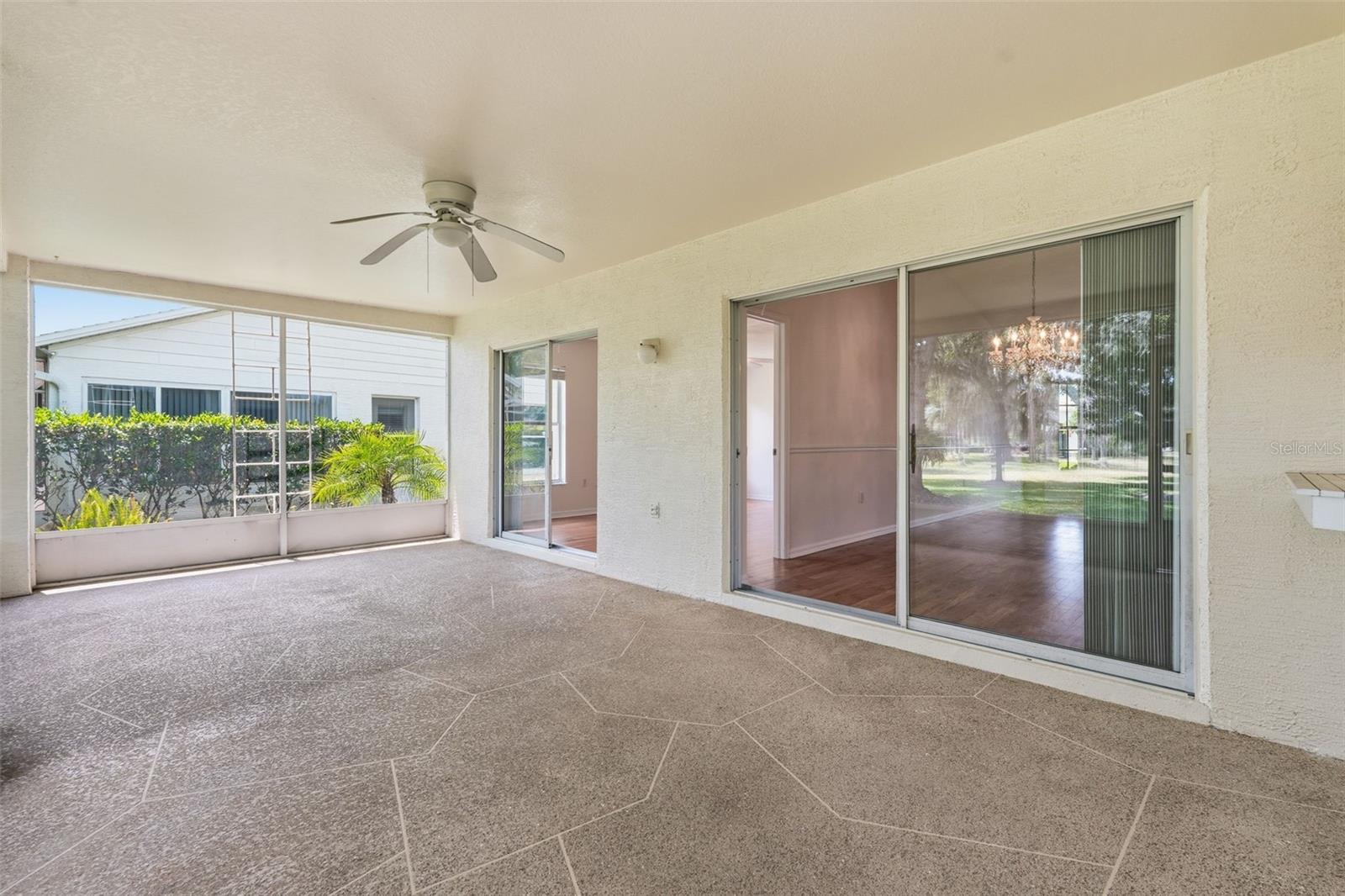 Covered screened patio with a tiled floor, ceiling fan, and sliding glass doors.