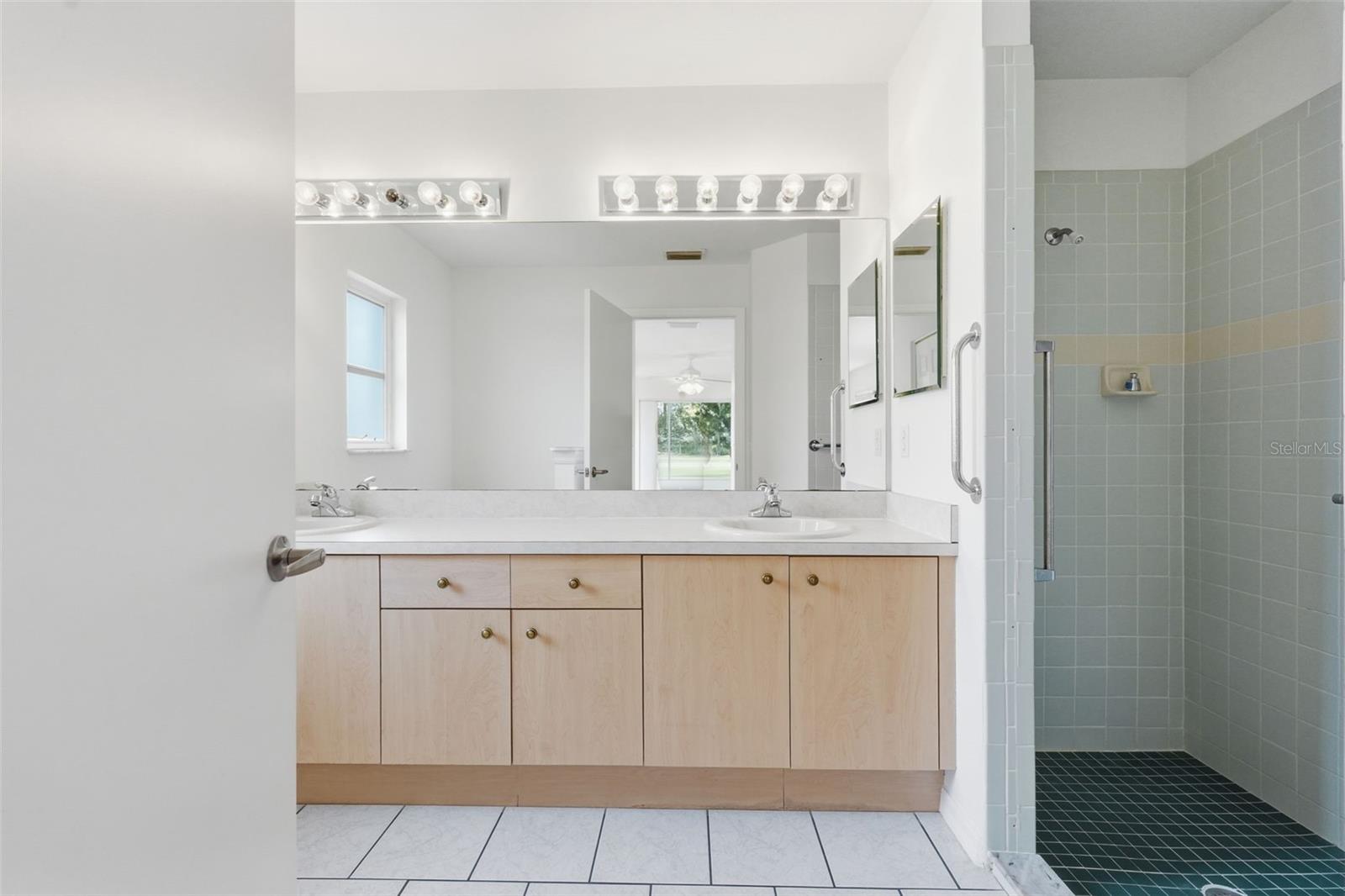 Bathroom with a long double-sink vanity and a tiled walk-in shower.