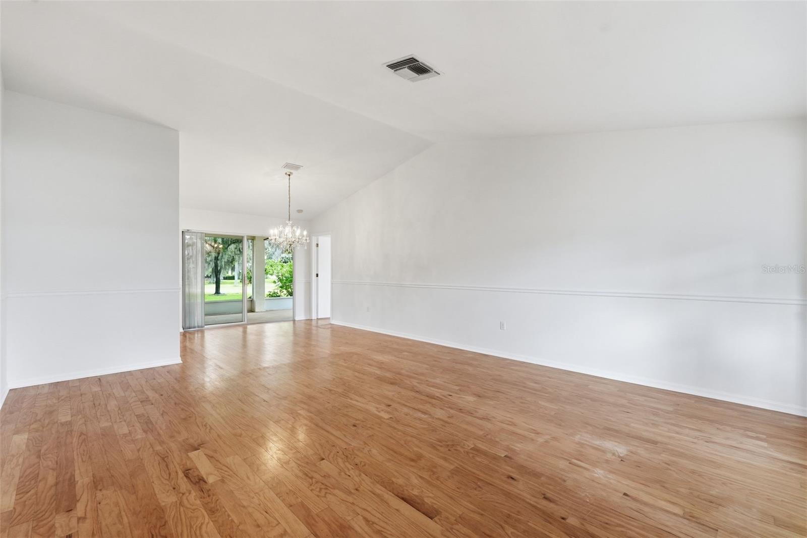 Empty dining room with hardwood floors, a chandelier, and sliding glass doors to the yard.