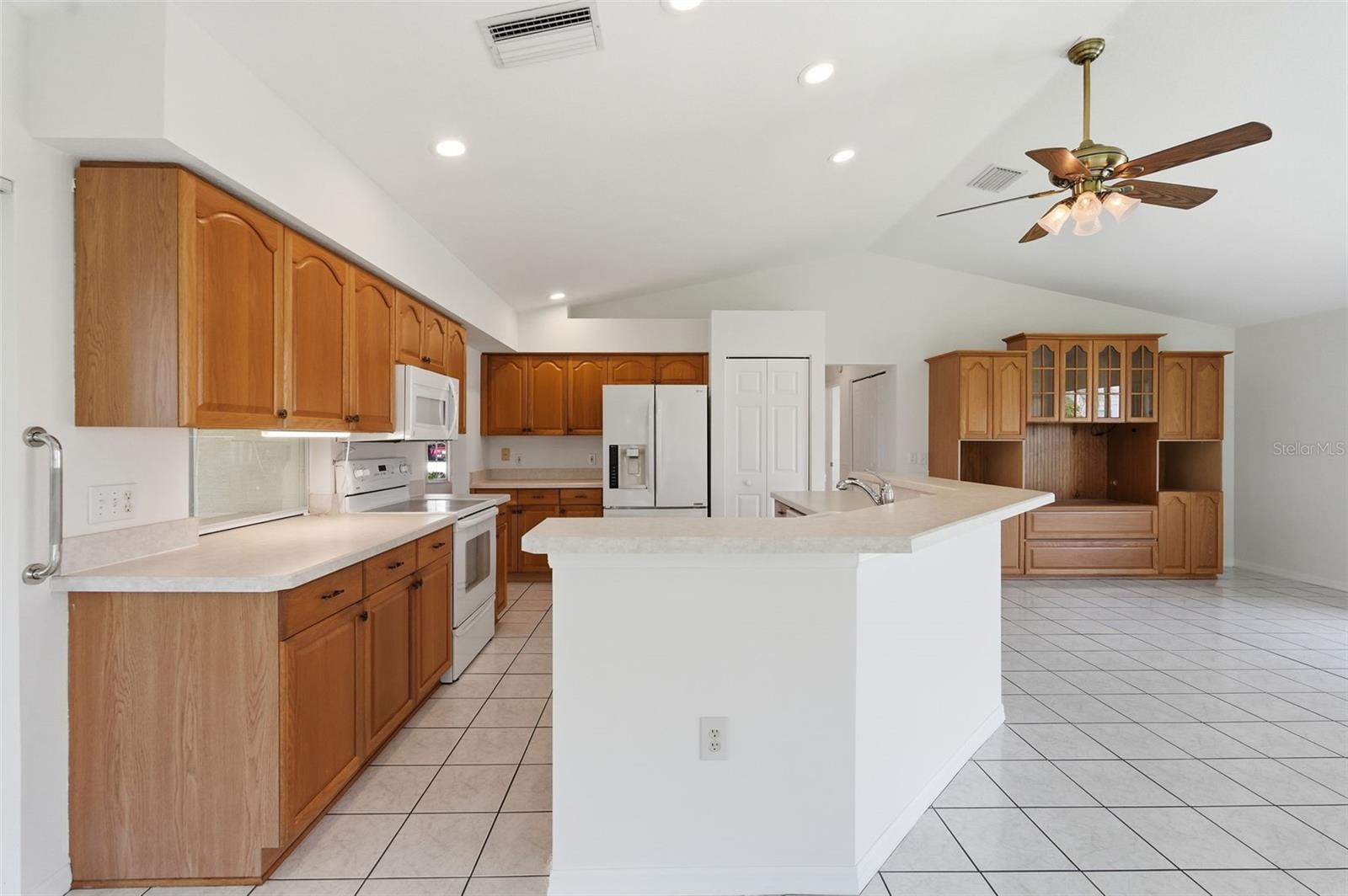 Spacious kitchen with a large white island, wood cabinetry, and stainless steel appliances.