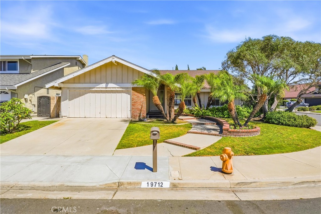 Single-story home with a wide garage, curved brick planter, and palm landscaping.