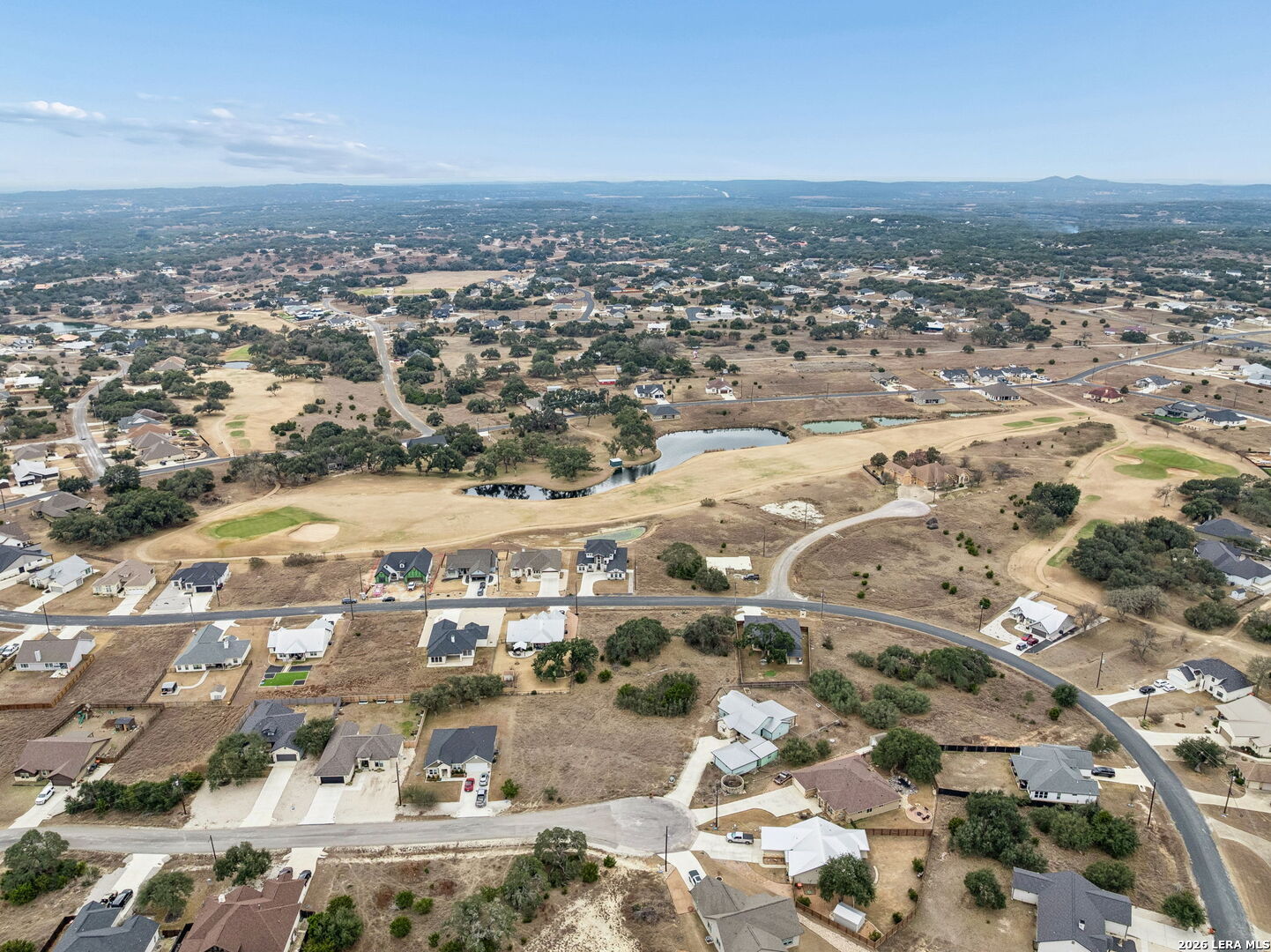 Aerial view of homes surrounding a golf course with ponds and winding roads.